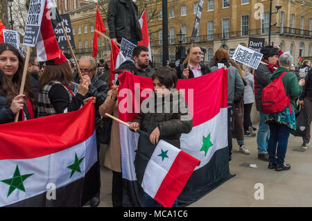April 13, 2018 - London, UK. 13th April 2018. Syrians with Syrian flags. Stop the War and Syrians protest at Downing St calling for Theresea May to stop her plans to bomb Syria with the USA and France following the reports of a chemical weapon attack there. Stop the War handed in a letter signed by MPs, trade unionists and others and held a rally on the opposite side of Whitehall, with speeches from Stop the War and other activists. Noisy chanting continued and many of those present crossed the road to protest outside Downing St before blocking both carriageways of Whitehall. After some minute Stock Photo