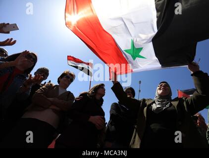 (180414) -- AMMAN, April 14, 2018 (Xinhua) -- Protesters wave Syrian flags during a protest following a wave of U.S., British and French military strikes on Syria in front of American embassy in Amman, Jordan, April 14, 2018. (Xinhua/Mohammad Abu Ghosh) (swt) Stock Photo