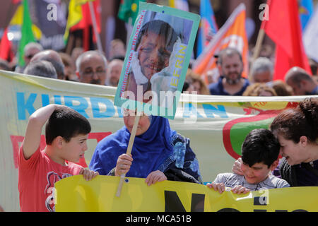 Mannheim, Germany. 14th April 2018. A protester carries a placard with the picture of an injured child. Kurdish people and German supporters marched through Mannheim to protest against the continued occupation of the Syrian city of Afrin, which was controlled by the Kurdish Popular Protection Units (YPG) before it got conquered by the Turkish army. They also protested against the German involvement via weapons exports to Turkey. Credit: Michael Debets/Alamy Live News Stock Photo