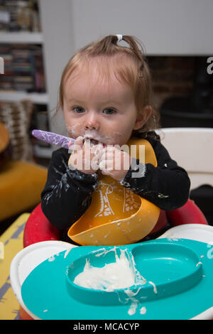 9 month old baby eating yoghurt - baby led weaning Stock Photo