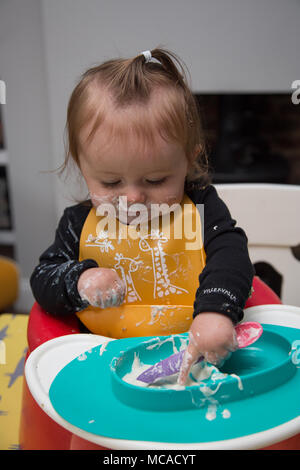 9 month old baby eating yoghurt - baby led weaning Stock Photo