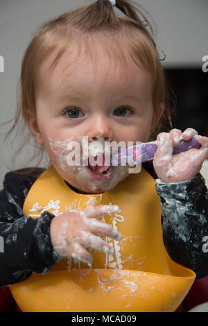 9 month old baby eating yoghurt - baby led weaning Stock Photo