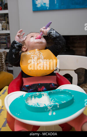 9 month old baby eating yoghurt - baby led weaning Stock Photo