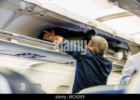 Miami Florida,International Airport MIA,airplane cabin,open carry on hand luggage baggage suitcase suitcases cabin compartment compartments,overhead l Stock Photo