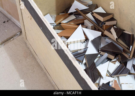 Furniture accessories. Waste production skirting boards in the furniture factory in the form of triangular scraps of different colors in a cardboard b Stock Photo