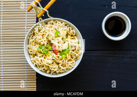 Bowl of instant cooked plain noodles with chopsticks and pepper garnish - Top view photo Stock Photo