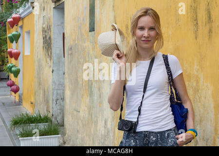 cheerful young woman tourist standing on street with camera Stock Photo