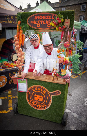 Kirkby Lonsdale, Cumbria / UK - April 15th 2018: Two men dress as chefs in a mobile kitchen at Taste Cumbria food festival in the market square. Stock Photo