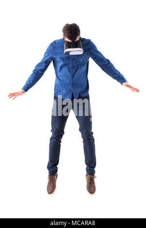 Surprised man wearing vr glasses jumping and looking down having virtual reality experience. Full body isolated on white background. Stock Photo