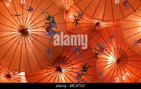 Oriental Chinese sun shade umbrellas with attractive design on a red silk surface used as lamp shades Stock Photo