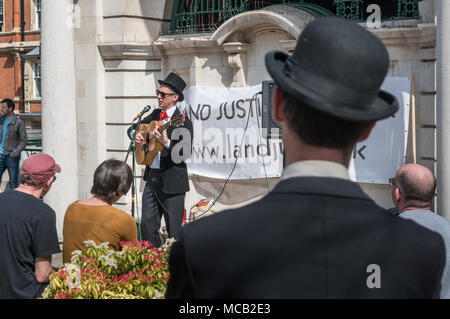 London, UK. 14th April 2018. Robin from the Land Justice Network sings at the start of the tour of London's wealthiest areas, led by the Land Justice Network demonstrates land ownership in Britain is one of the most unequal in the world, both in rural areas and in cities. The tour began in Westminster, largely owned by the Duke of Westminster, stopping at relevant points on the Grosvenor Estate, Park Lane, in Hyde Park, Grosvenor Crescent and Belgrave Square for information and speeches, ending on the 93 acres of the Cadogan Estate, the wealthiest part of Kensington & Chelsea for a final rally Stock Photo