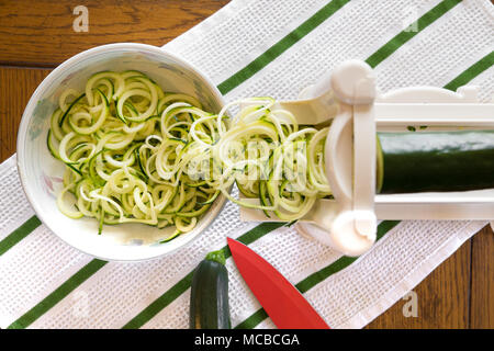 Spiral zucchini noodles called zoodles prepared in spiralizer kitchen gadget Stock Photo