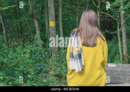 Girl in yellow sweater sitting on bench