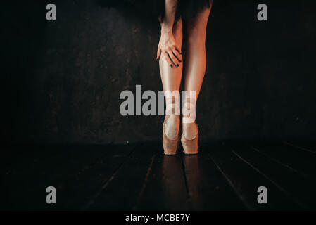 Ballet dancer legs in pointes, black wooden floor Stock Photo