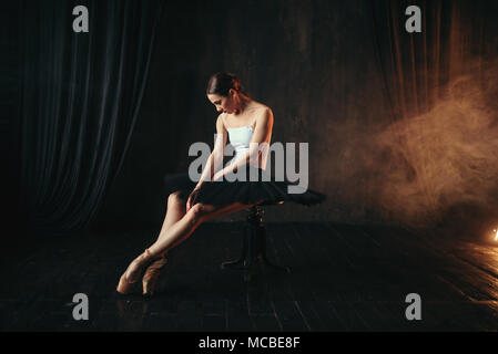 Ballet dancer sitting on black banquette Stock Photo