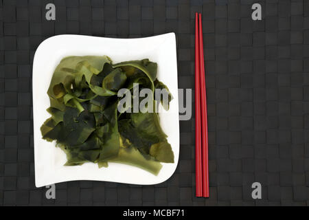 Japanese wakame seaweed food with on bamboo background with red chopsticks. Has many health benefits and is very high in minerals. Stock Photo