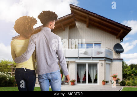Rear View Of A Young Couple Standing In Front Of House Stock Photo