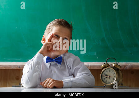 Boring school boy with alarm clock awaiting for something Stock Photo