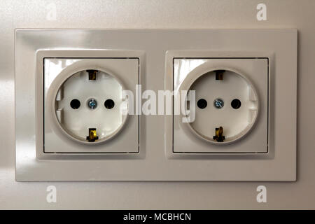 New white shiny plastic electric double sockets on white wall background. Advantages and comfort of modern homes. Stock Photo