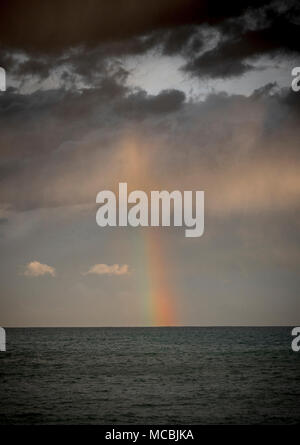Rainbow with dark clouds over the sea, dramatic atmosphere Stock Photo