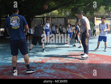 HONG KONG (March 28, 2018) Sailors assigned to the Arleigh Burke-class guided-missile destroyer USS Sterett (DDG 104) play basketball with students from the Yan Chai Hospital Secondary School during a cultural exchange event. Sterett is in Hong Kong to experience the city’s rich culture and history as the guided-missile destroyer continues its deployment with the Wasp Expeditionary Strike Group as a multi-mission asset in the Indo-Pacific region. Stock Photo