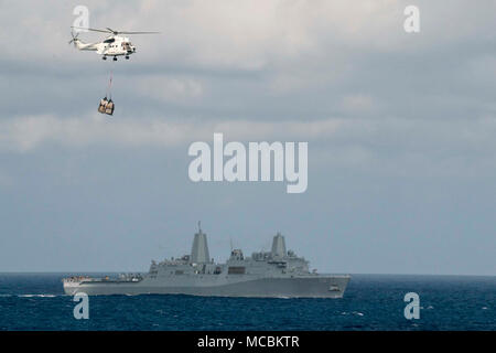 PHILIPPINE SEA (March 29, 2018) The amphibious transport dock ship USS Green Bay (LPD 20) steams through the Philippine Sea as an SA-330 Puma helicopter, assigned to the dry cargo and ammunition ship USNS Wally Schirra (T-AKE 8), transports supplies during a replenishment-at-sea with the Wasp Expeditionary Strike Group (ESG). Green Bay, as part of the Wasp ESG, is operating in the Indo-Pacific region as part of a regularly scheduled patrol and provides a rapid-response capability in the event of a regional contingency or natural disaster. Stock Photo