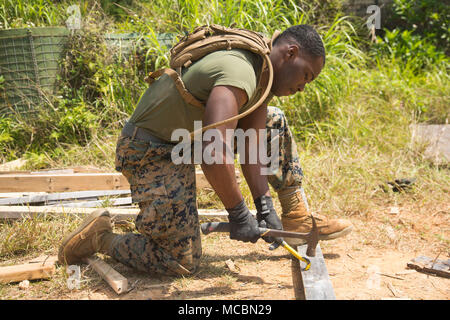 Lance Cpl. Karenz Wright, a combat engineer with 2nd Platoon, A Co., 9th Engineer Support Battalion, 3rd Marine Logistics Group, removes nails from a former Southwest Asia Hut used during different training exercises March 26, 2018, Camp Hansen, Okinawa, Japan. Vertical construction training prepares Marines for similar projects they will be entrusted with during humanitarian assistance operations. The engineers were tasked to remove the nails from the wood and dispose of them separately due to Defense Reutilization Marketing Office (DRMO) regulations. Wright is a native of Saint Louis, Missou Stock Photo