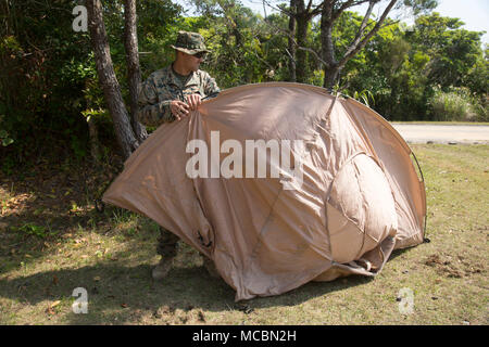 Lance Cpl. Kyle Harris, a combat engineer with 1st Platoon, A Co., 9th Engineer Support Battalion, 3rd Marine Logistics Group, sets up a tent to sleep in for the week while conducting vertical construction training, March 26, 2018, Camp Hansen, Okinawa, Japan.  The Marines stayed out in the field until the vertical construction of an ammunition storage point was completed, going to sleep around midnight every night and getting up around 6:00 a.m. every morning. Harris is a native of Antonio, Texas. Stock Photo