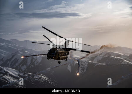 A U.S. Army Task Force Brawler CH-47F Chinook releases flares while conducting a training exercise with a Guardian Angel team assigned to the 83rd Expeditionary Rescue Squadron at Bagram Airfield, Afghanistan, March 26, 2018. The Army crews and Air Force Guardian Angel teams conducted the exercise to build teamwork and procedures as they provide joint personnel recovery capability, aiding in the delivery of decisive airpower for U.S. Central Command. Stock Photo