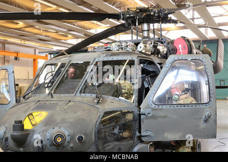 (From left to right) Mr. Donald Camp, a  Logistics Assistance Representatives (LARs), with the United States Army Aviation and Missile Command (AMCOM) and Soldiers from C Company, 2-227th Aviation Regiment, 1st Air Cavalry Brigade from Fort Hood Texas conducts main rotor system maintenance on a HH-60 MEDEVAC helicopter, March 27, 2018, at Katterbach Army Airfield in Ansbach, Bavaria, Germany. LARs are the technical experts who have the skills and experience to provide technical assistance for on-site repairs to increase readiness and reduce cost. The LARs work closely with the units to support Stock Photo