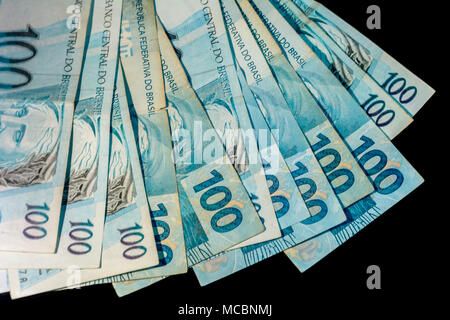 Brazilian money one hundred bills (cem reais) isolated on black background. Money and finance concept. Stock Photo