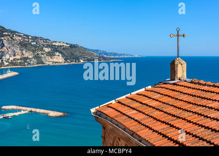 Church roof with cross overlooking Mediterranean sea and shoreline of Menton - small town on French Riviera. Stock Photo