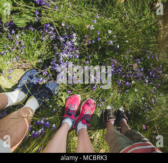 Legs of traveler family standing on green grass high in the mountain. Freedom concept. top view Stock Photo