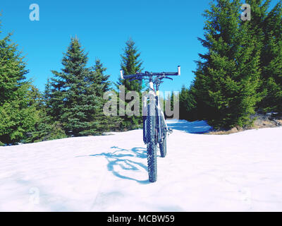 Mountain bike stay in powder snow. Lost path in deep snowdrift.  Snow flakes melting on dark off road tyre. Winter weather in the field. Stock Photo