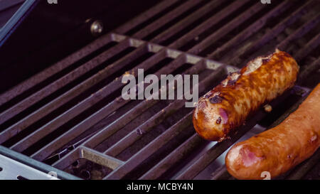 Cooking hot dogs and bratwurst on outdoor gas grill in the Summer. Stock Photo