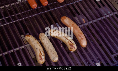 Cooking hot dogs and bratwurst on outdoor gas grill in the Summer. Stock Photo