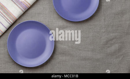Empty purple plates on grey burlap tablecloth background Stock Photo