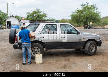 A man fills up gasoline for a car at a rural petro station. Colombia, South America. Stock Photo