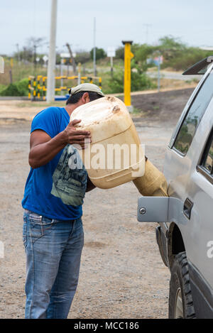 A man fills up gasoline for a car in a rural petro station. Colombia, South America. Stock Photo