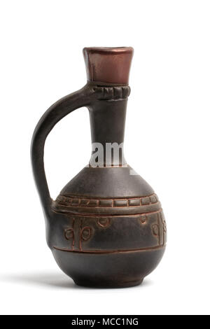 A small brown clay jug with patterns and a narrow high neck close-up view isolated on a white background. Stock Photo