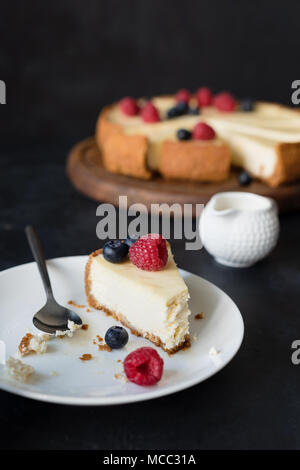 Slice of cheesecake with missing bite on white plate. selective focus Stock Photo