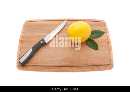 yellow lemon with green leaves and a knife on a wooden kitchen c Stock Photo