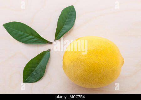 yellow bright lemon with three green leaves close-up on a cuttin Stock Photo
