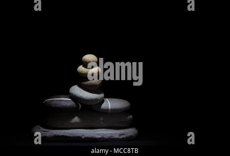Stacked Stones under a soft light on a black background Stock Photo