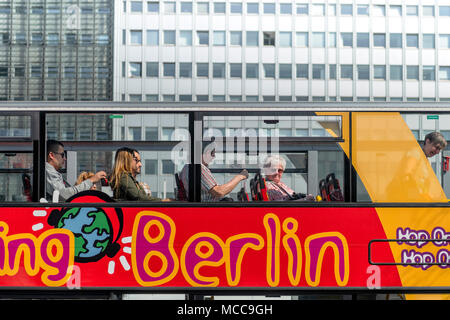 People sit on the top deck of one of the many 'Hop On, Hop Off' buses that are a major tourist attraction in the German capital of Berlin. Stock Photo