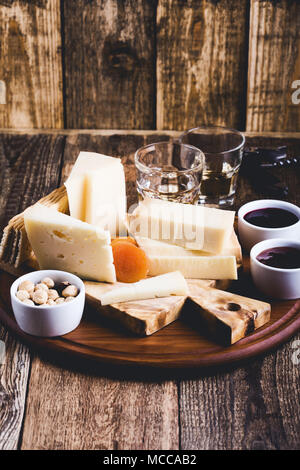 Cheese platter, fruit jam, nuts and wine on wooden cutting board, delicious holiday appetizer Stock Photo