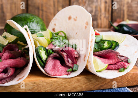 Tacos with beef steak and vegetables on wheat flour tortillas, Mexican style meal Stock Photo