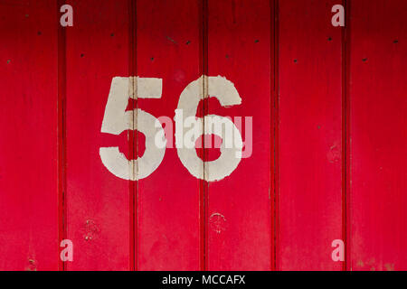 Crudely painted number fifty-six in white paint on a red door Stock Photo