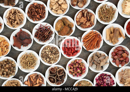 Traditional chinese herbs used in alternative herbal medicine in white porcelain bowls on marble background. Stock Photo