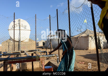 DJIBOUTI , Obock, refugee camp Markazi for yemeni war refugees, girl fetch water from tap, slogan water is life written on tank / DSCHIBUTI, Obock, Fluechtlingslager Markazi fuer jemenitische Fluechtlinge, Wasserstelle Stock Photo